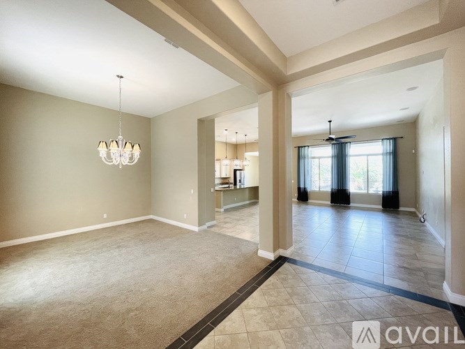 A spacious room with a chandelier and a large mirror on the wall.