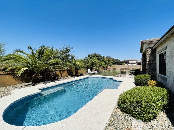 A swimming pool surrounded by a concrete border and a small garden.
