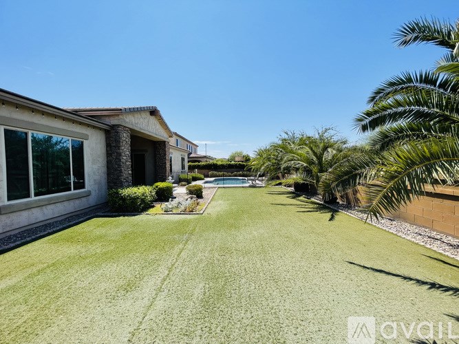 A house with a lawn and a pool in the backyard.