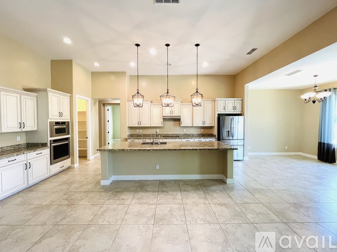 A spacious kitchen with a central island and pendant lights.
