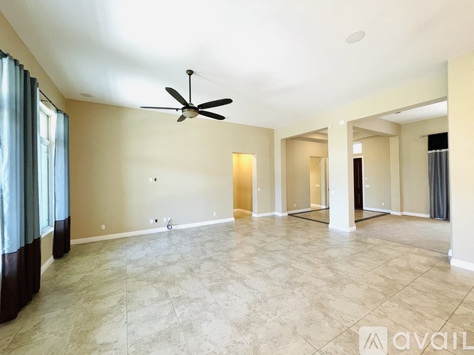 A spacious room with a ceiling fan and tiled flooring.