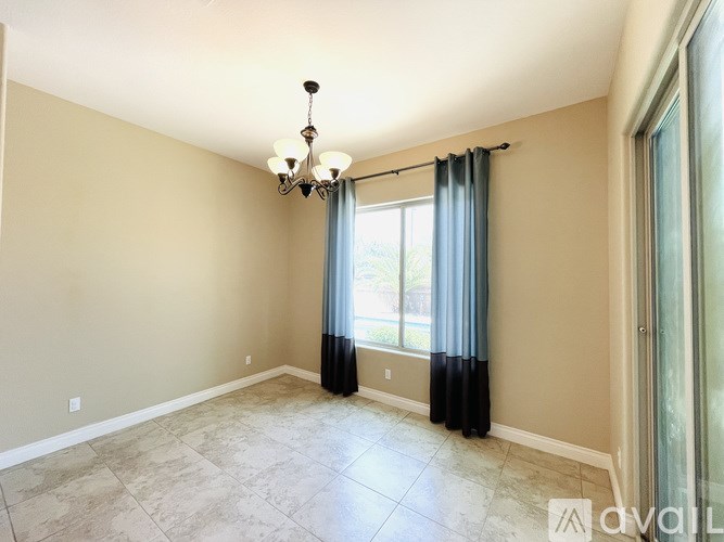 A room with a chandelier, curtains, and tiled floor.
