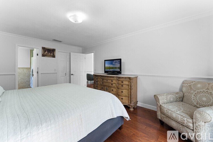 A bedroom with a bed, a chair, and a television.