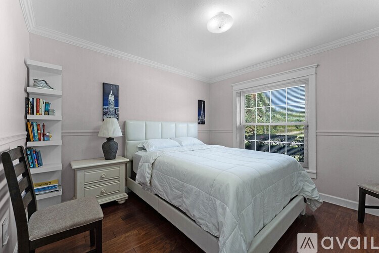 A bedroom with a large bed, a chair, a nightstand, and a window.