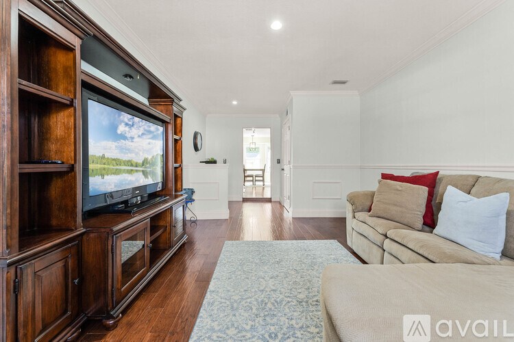 A living room with a wooden entertainment center and a beige couch.