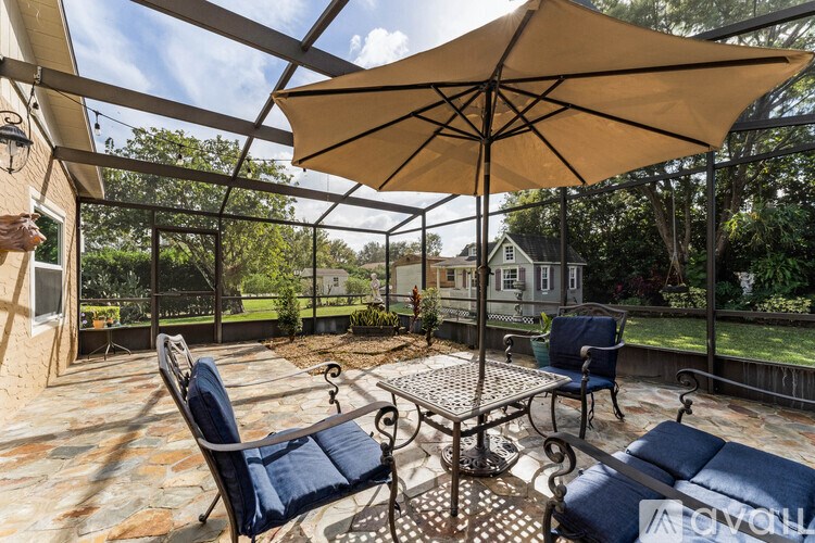A patio with a table, chairs and an umbrella.