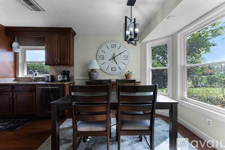 A kitchen with a table and chairs and a clock on the wall.