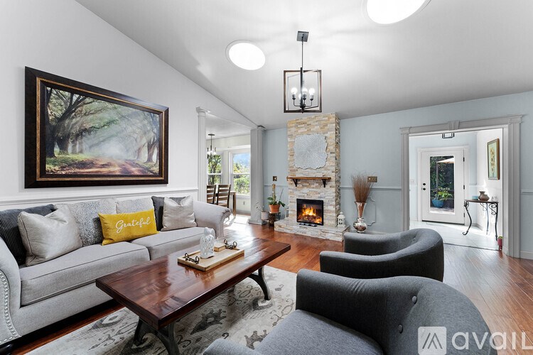 A living room with a grey couch, a coffee table, and a painting on the wall.