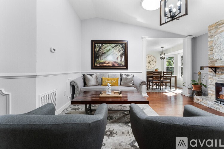 A living room with a grey couch and a painting on the wall.