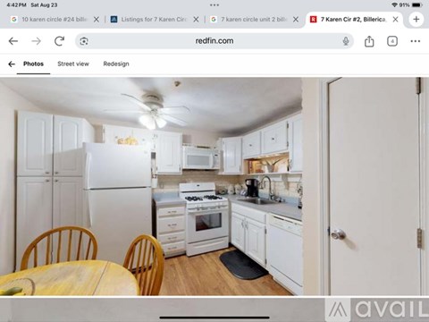 A kitchen with white appliances and wooden chairs.