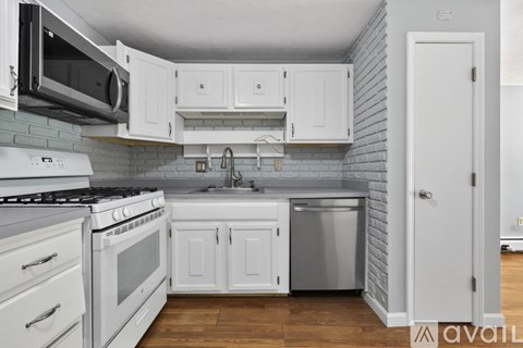 A kitchen with white cabinets and a stove top oven.