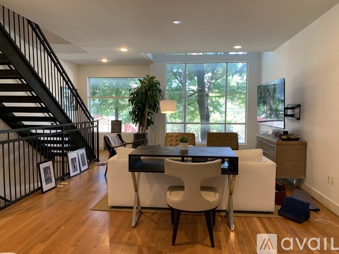 A modern living room with a staircase on the left and a dining area in the center.