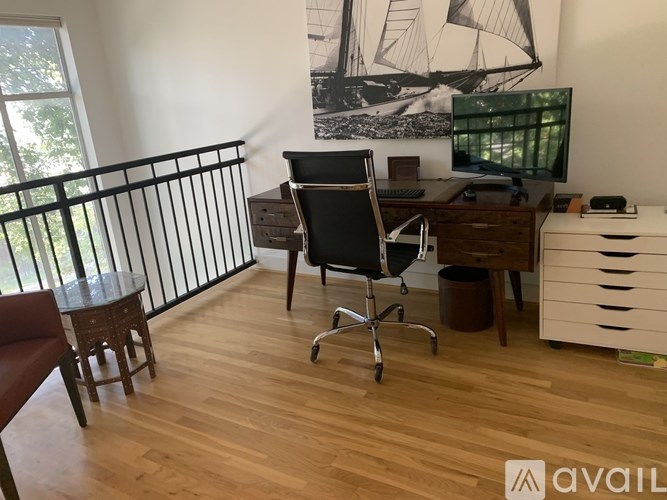A room with a desk, chair, and a painting on the wall.