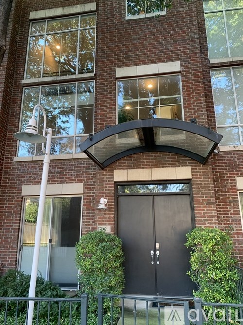 A building with a black door and windows with a sign on the fence.