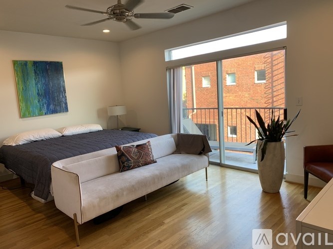 A bedroom with a bed, a couch, and a ceiling fan.