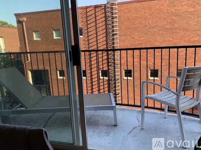 A balcony with a chair and a table overlooking a brick building.