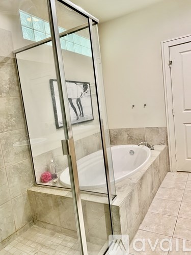 A bathroom with a glass shower door and a white door.