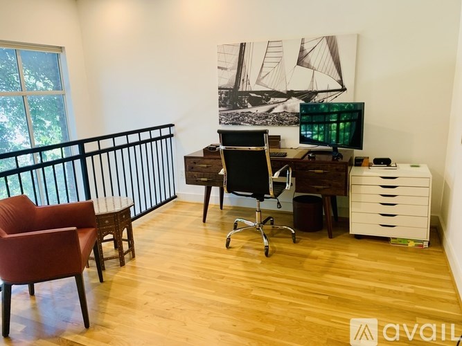 A room with a desk, chair, and a painting on the wall.
