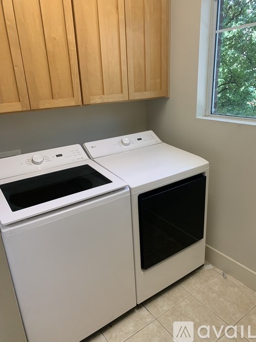 Two white ovens in a kitchen with wooden cabinets.