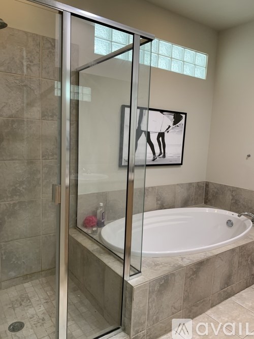 A bathroom with a tub and a glass shower door.