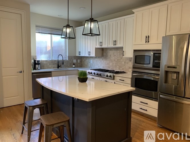 A kitchen with white cabinets and a dark island.