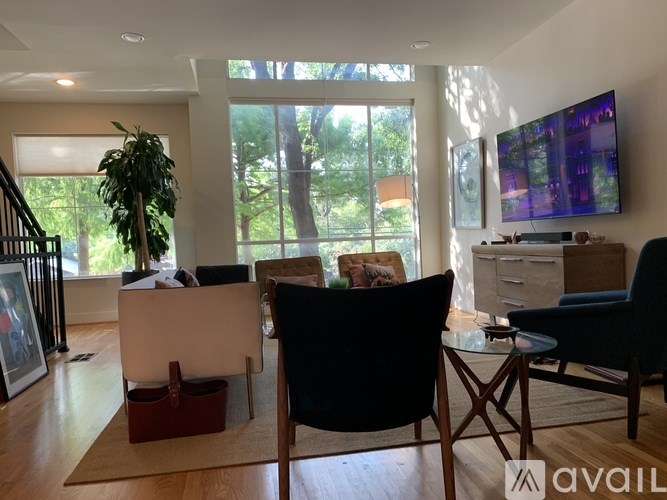 A living room with a white couch, a black chair, and a glass table.