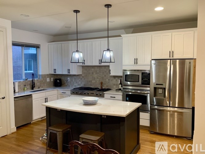 A modern kitchen with stainless steel appliances and wooden floors.