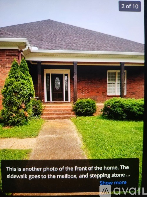 A house with a front porch and a sidewalk leading to a mailbox.