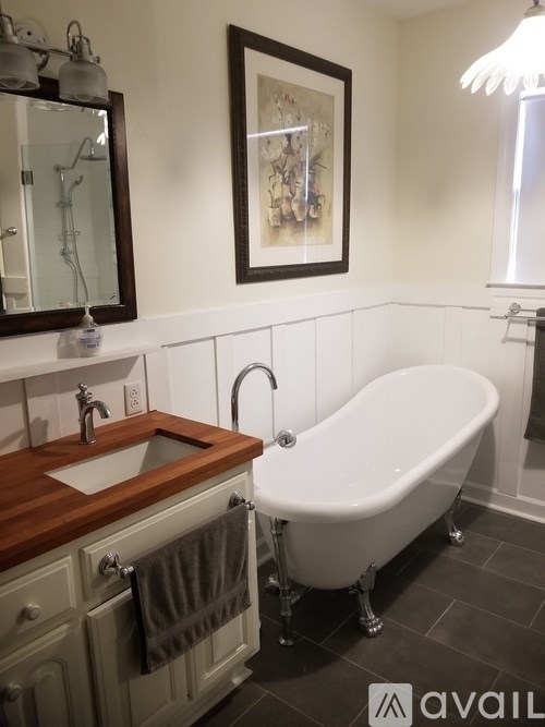 A white claw foot tub sits next to a sink in a bathroom.