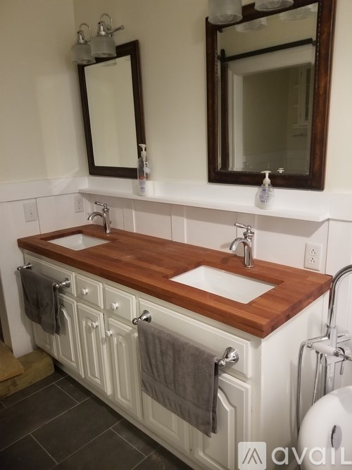 A bathroom with two sinks and a wooden counter top.