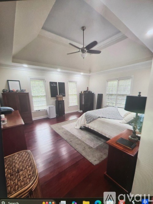 A bedroom with a bed, chair, and ceiling fan.