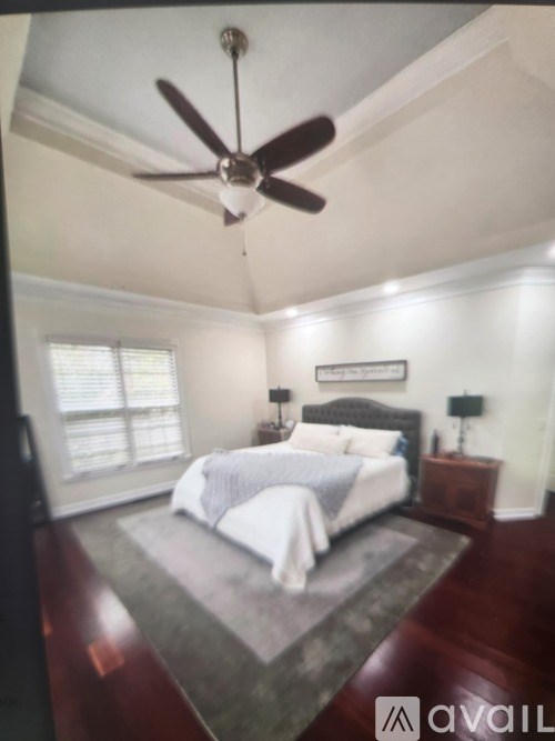 A bedroom with a bed, nightstand, and ceiling fan.