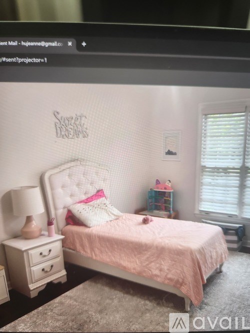A bedroom with a pink bed and a white nightstand.
