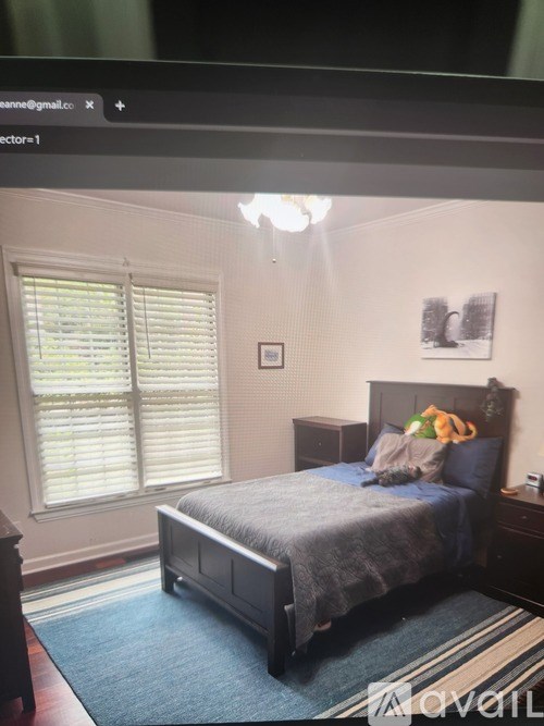 A bedroom with a bed, nightstand, and window with blinds.