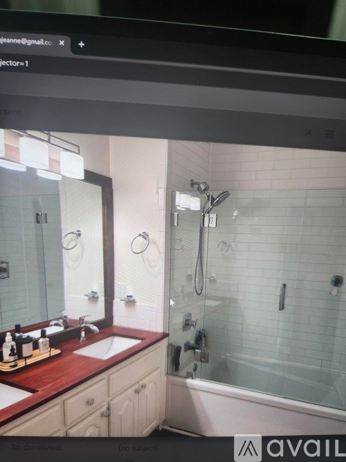 A bathroom with a sink, mirror, and shower.