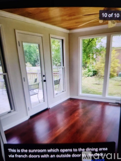 A sunroom with a view of a dining area and a lawn outside.