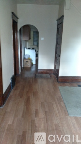 A hallway with wooden floors and a doorway leading to another room.