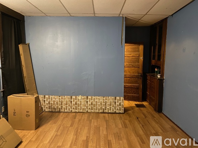 A room with wooden floors and a blue wall with a door on the right side.