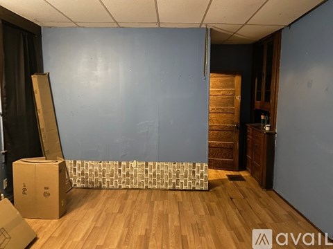 A room with wooden floors and a blue wall with a door on the right side.