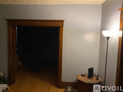 A dark room with a wooden door and a small table with a speaker on it.