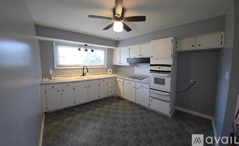 A kitchen with white cabinets and a fan on the ceiling.