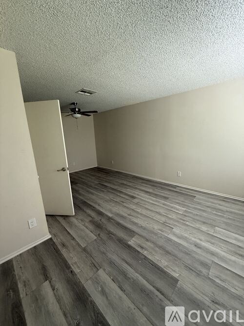 A room with a ceiling fan and wood flooring.