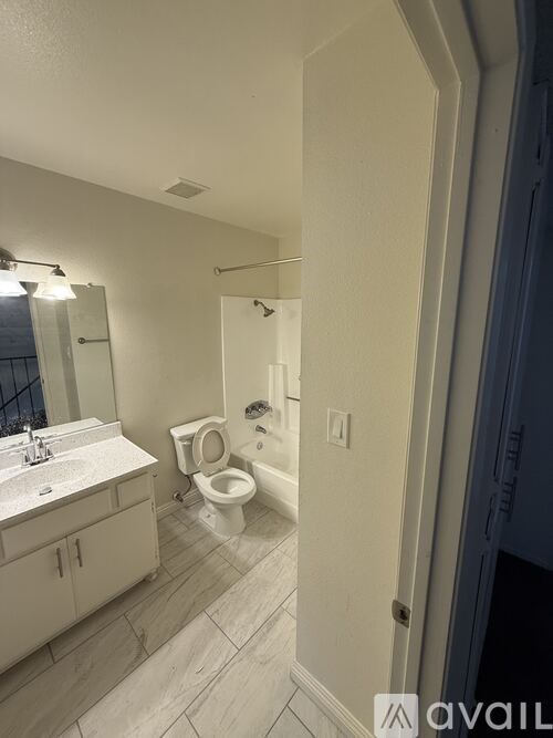 A bathroom with a toilet, sink, and mirror.