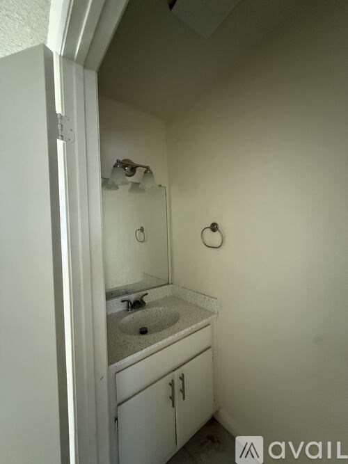 A small white bathroom with a sink and mirror.
