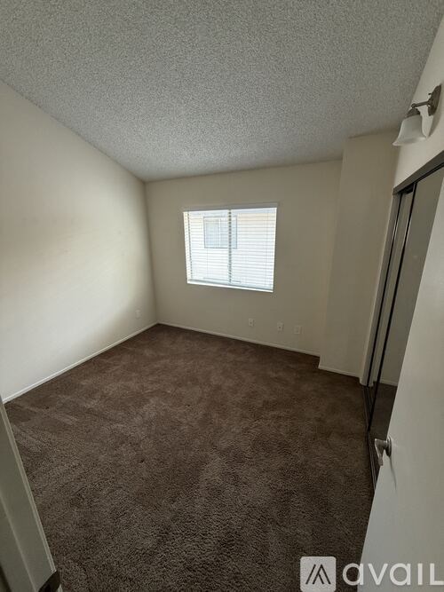 A room with a carpeted floor and a window with blinds.