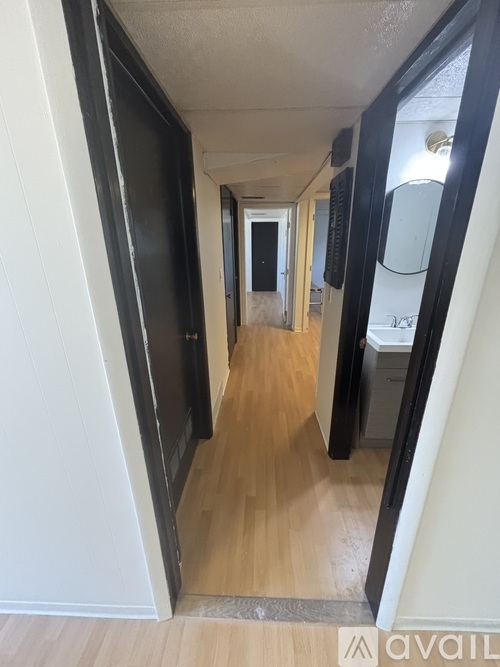 A hallway with a black door on the left and a white door on the right.