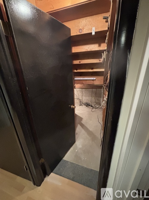 A black refrigerator is open in a room with a wooden ceiling.