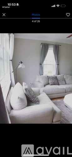 A living room with white furniture and a window with curtains.