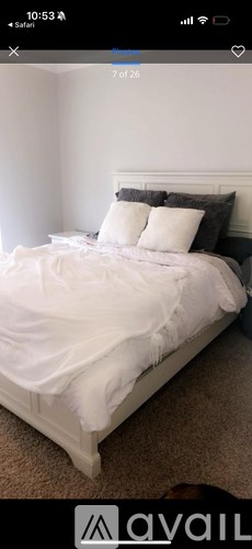 A bed with white sheets and pillows in a room.