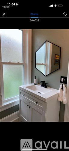 A white sink vanity with a mirror and a window.